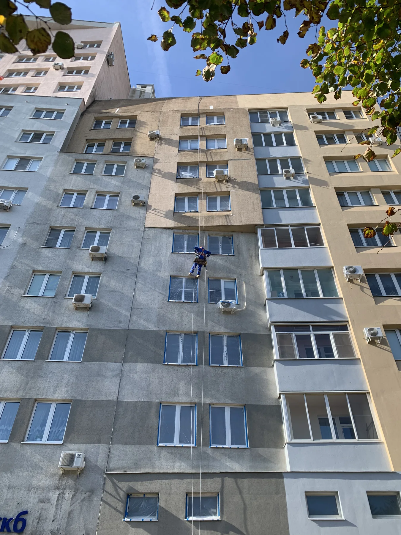 Промышленный альпинист выполняет утепление стены многоквартирного дома